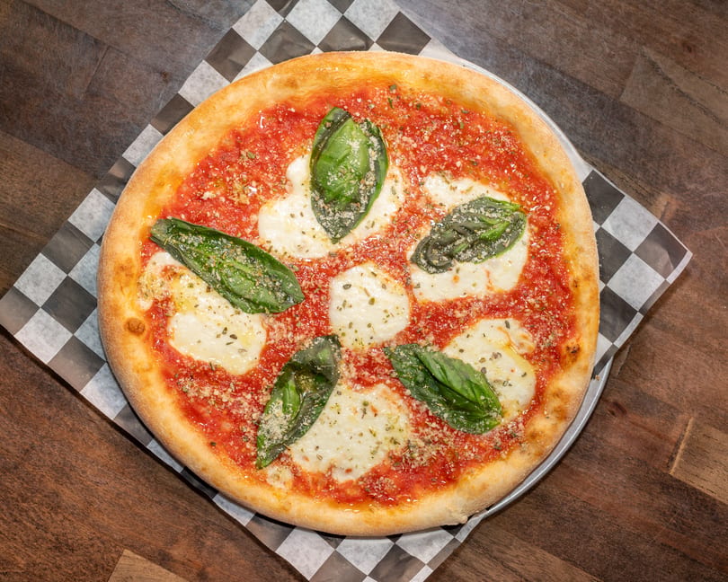 A freshly baked Margherita pizza with vibrant red sauce, melted mozzarella, and fresh basil leaves.