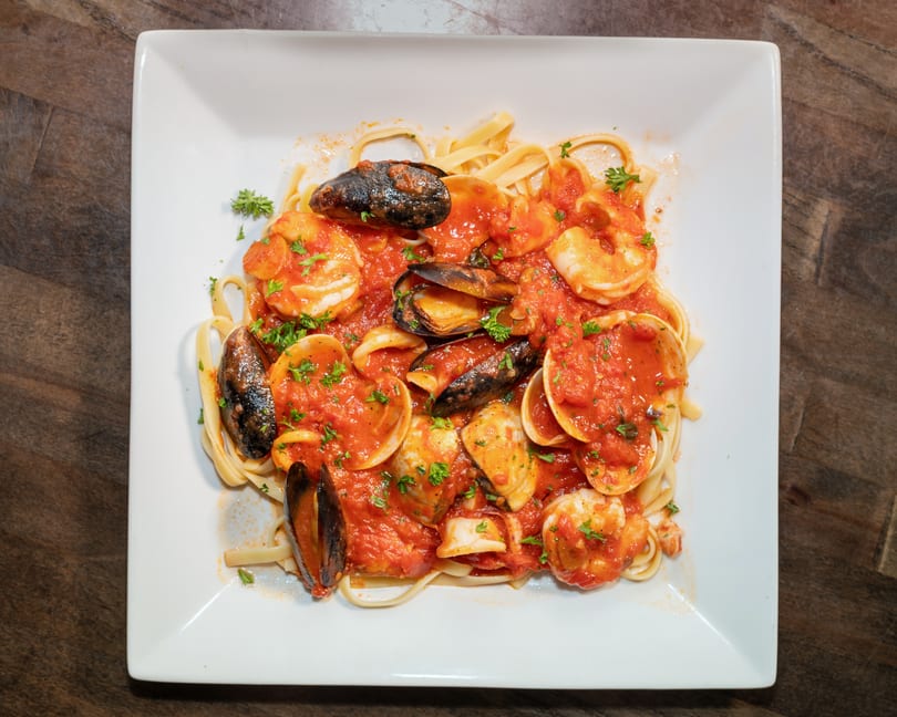 Seafood linguine with shrimp, mussels, and clams in a rich red tomato sauce, garnished with parsley.