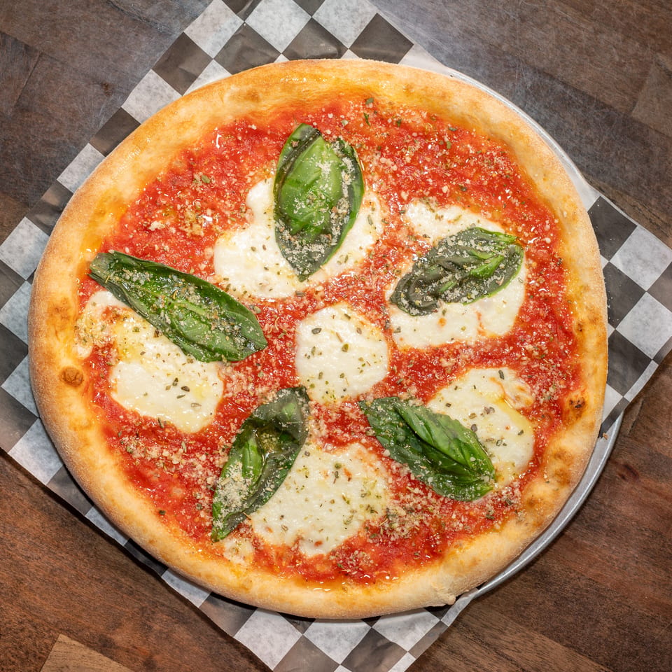 A freshly baked Margherita pizza with vibrant red sauce, melted mozzarella, and fresh basil leaves.